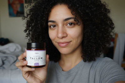 Eine Frau mit einem Glas Beef Tallow Creme in einer Hand